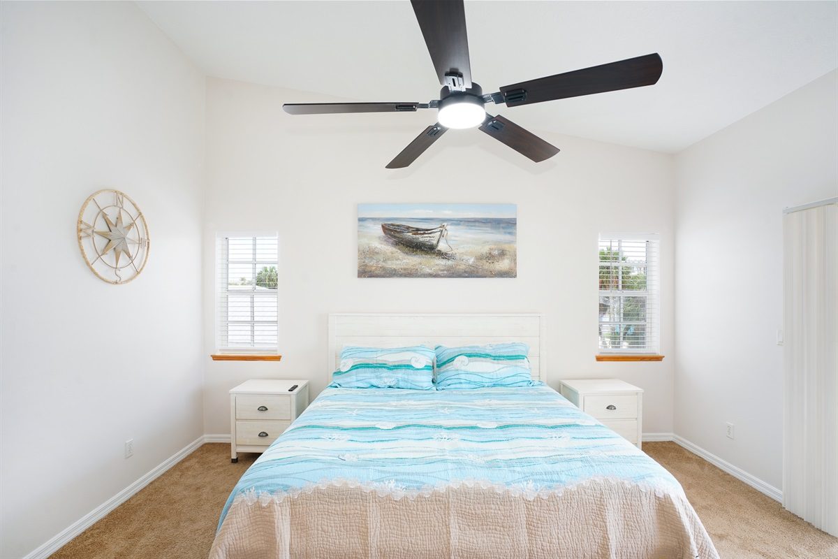 Bedroom with a queen bed and beach art at Coastal Getaway