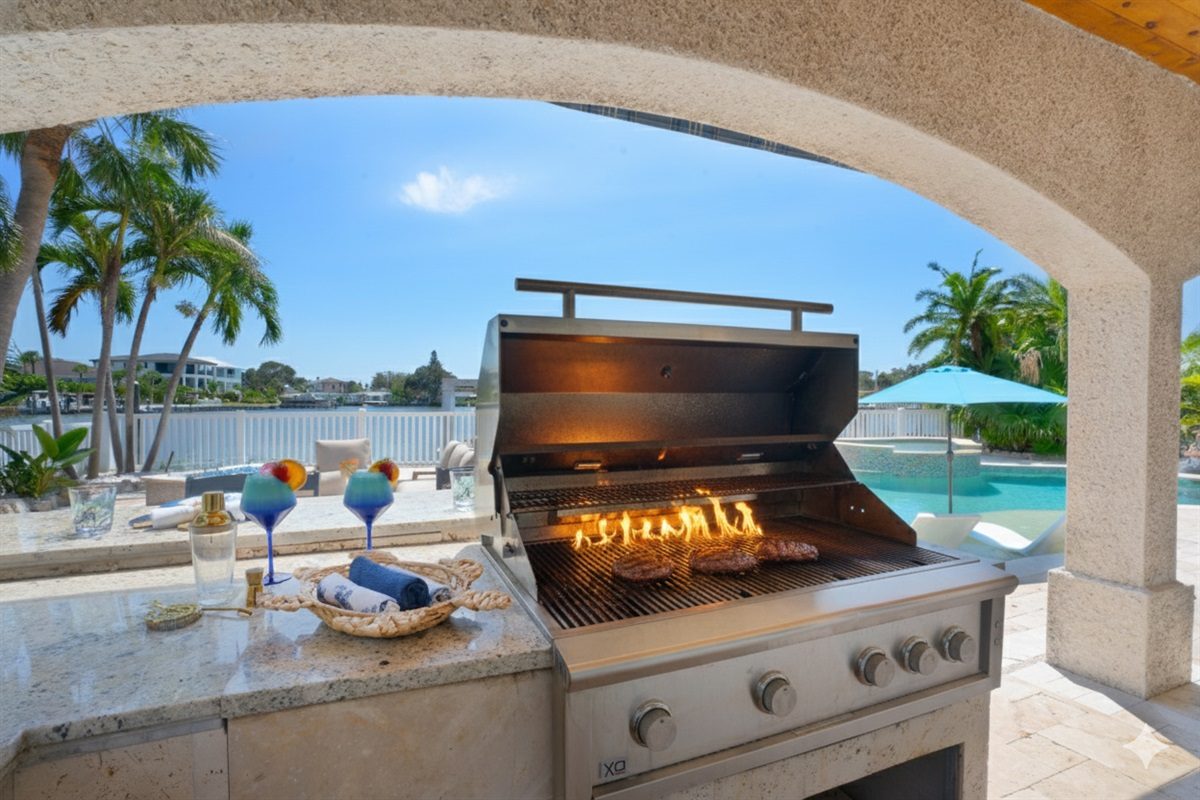 Outdoor kitchen with a stainless steel grill under the arched patio at Coastal Manor