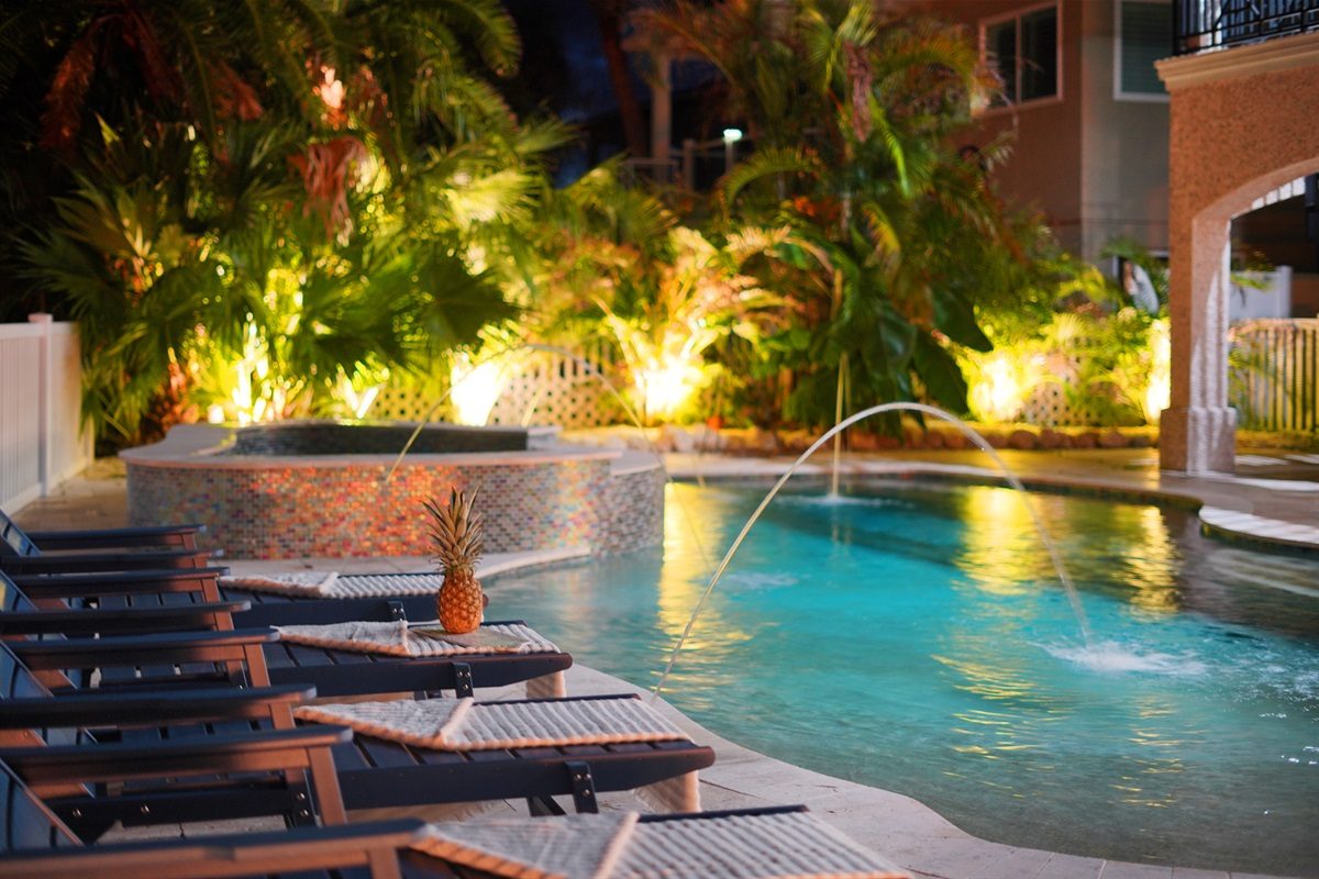 Coastal Manor spa spilling into the heated pool, lit up at dusk