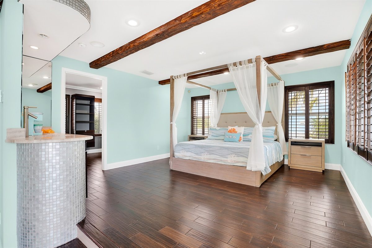Primary suite with a canopy bed at Coastal Manor