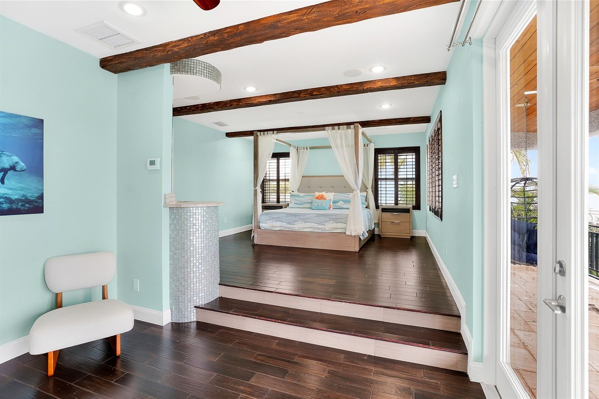 Primary suite with a raised canopy bed at Coastal Manor