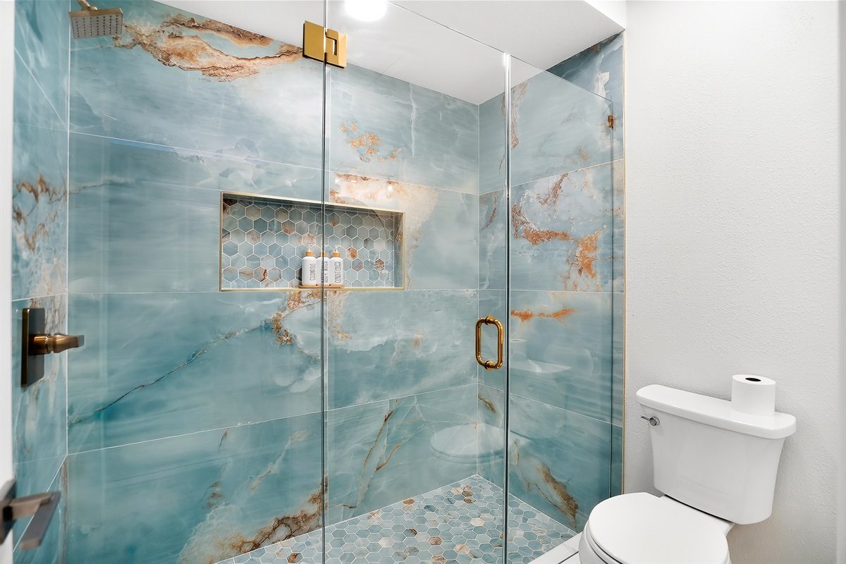 Walk-in shower with marble-look tile at Coastal Manor