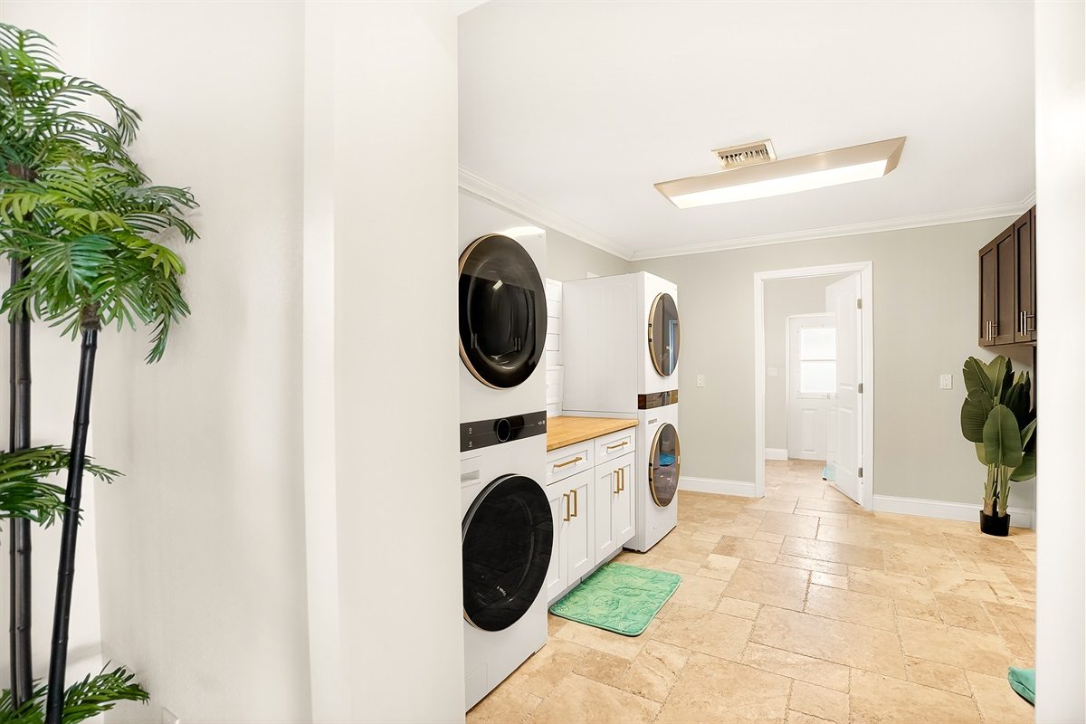 Laundry room with two stacked washers and dryers at Coastal Manor