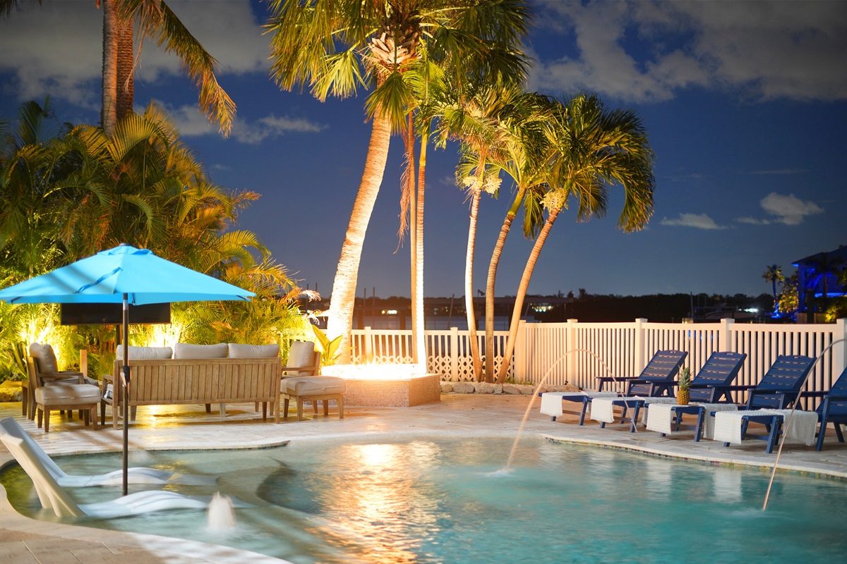 Coastal Manor pool and fire pit at dusk with palm trees
