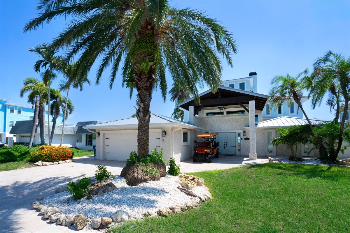 Front of Coastal Manor with palm trees and a landscaped lawn